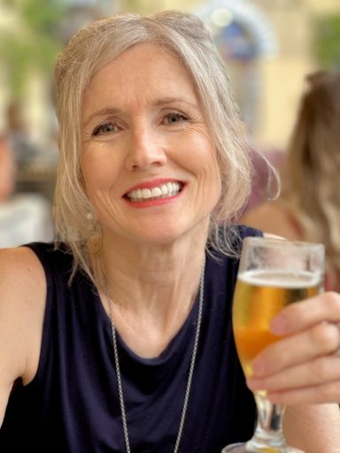 Smiling mature female model holding a drink in casual lifestyle setting