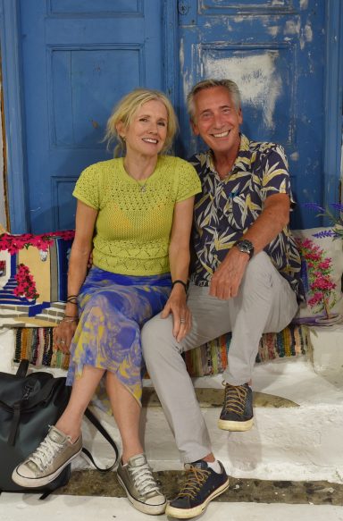 Mature lifestyle modelling couple seated together in colourful travel setting