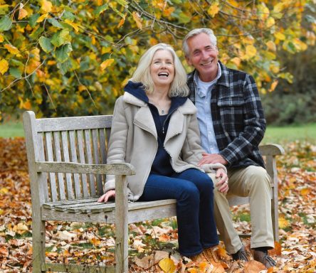 Middle-aged modelling couple seated on garden bench in autumn lifestyle setting