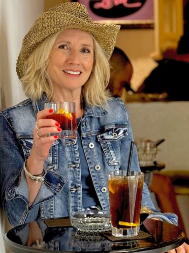 Mature lifestyle model holding drink while wearing denim jacket and hat