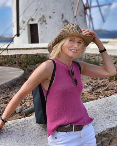 Mature lifestyle model wearing sleeveless top and hat in outdoor travel setting